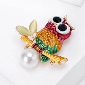 Macro shot of colorful enamel owl brooch with black crystal eyes and white pearl drop
