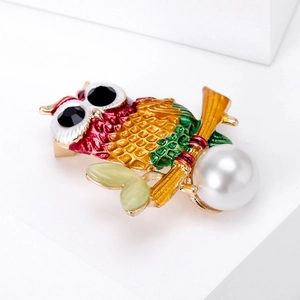 Detail of colorful enamel owl brooch with pearl drop and emerald green leaf accents