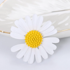 Elegante spilla a margherita bianca con centro giallo su un vassoio di ceramica