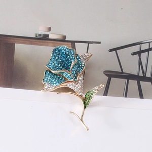 Close-up of elegant rose brooch with blue and green crystals on gold-plated metal base
