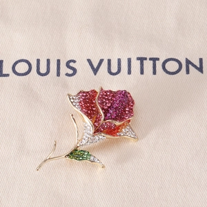 Macro shot of rose brooch with colorful rhinestones and gold-plated floral details