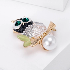 Detailed close-up of enamel owl brooch with green gem eyes and large white pearl