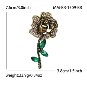 Elegant rose brooch with golden base, yellow crystals and green leaves on white background