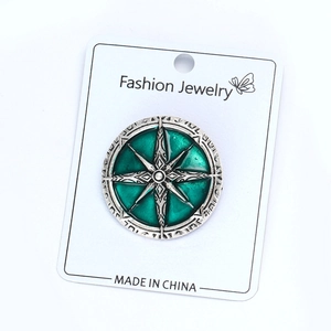 Détail macro d'une broche boussole rétro en alliage avec émail vert sur carte de support