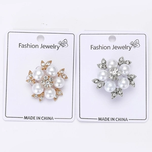 Detailed view of elegant flower brooches with white pearls and rhinestones on cards