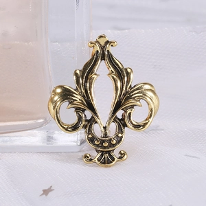 Detail of vintage fleur-de-lis brooch in antique gold finish with intricate baroque patterns