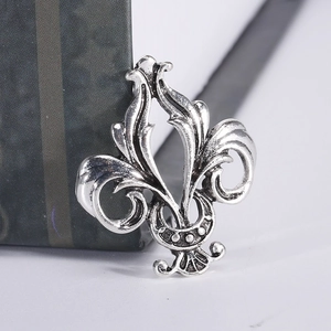 Macro shot of antique silver fleur-de-lis brooch with vintage gothic metal textures
