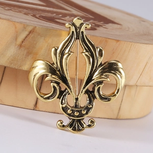 Macro detail of golden vintage fleur-de-lis brooch with antique embossed finish