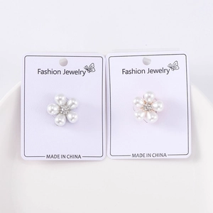 Détail de deux broches fleurs en perles avec strass présentées sur des cartes