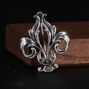 Macro shot of retro metal fleur-de-lis brooch with oxidized vintage finish detail