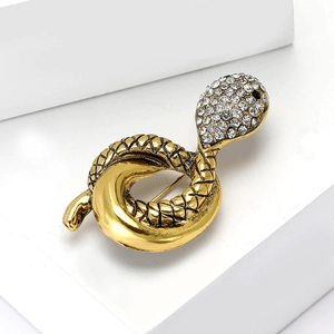 Vintage gold snake brooch with crystal rhinestones on white stone minimalist background