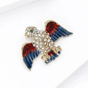 Detail of an eagle brooch featuring red and blue enamel wings and sparkling white crystals