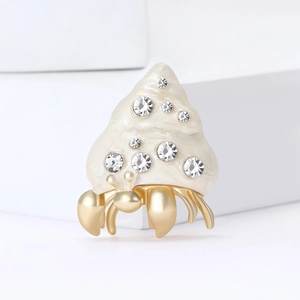 Artistic hermit crab shell brooch in white enamel and gold metal with crystals