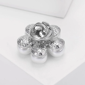 Gros plan d'une broche fleur en perles avec texture argentée et fermoir papillon