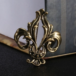 Detailed macro view of vintage bronze Fleur-de-lis brooch with antique metal texture
