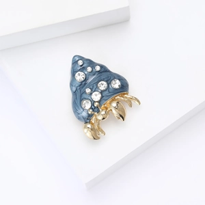 Detailed shot of an enamel hermit crab brooch with blue marble shell and crystals
