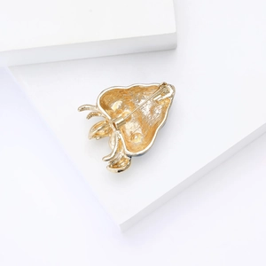 Macro detail of gold-tone strawberry brooch back showing a secure safety pin closure