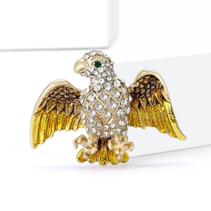 Detail of gold eagle brooch with white crystals and brown enamel feathers on a white background