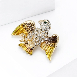 Macro shot of eagle brooch with golden base, crystal settings and enamel details