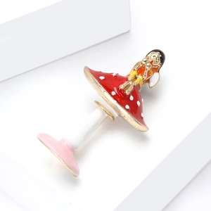 Détail de la broche émaillée avec robe rouge à pois et finitions dorées brillantes