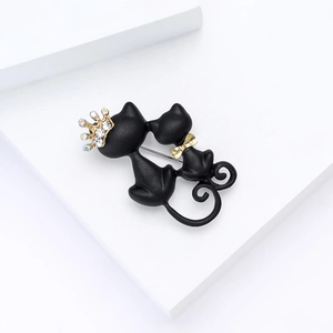 Matte black cat brooch with gold crown and crystals on white geometric stones
