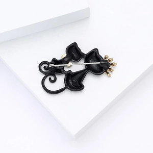 Detail showing the matte black alloy back of a cat brooch with a silver safety pin clasp