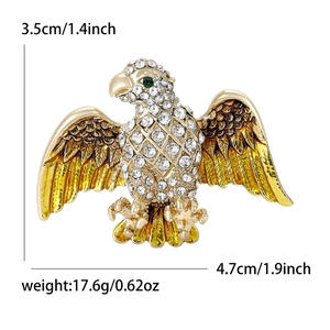 Golden eagle brooch with crystals and yellow enamel on white background including dimensions