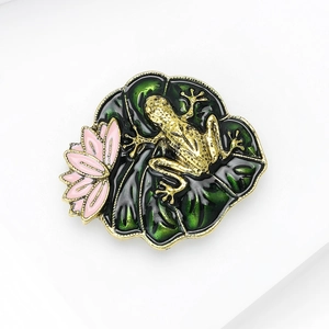 Vintage enamel frog brooch with green lotus leaf and pink flower on a white base