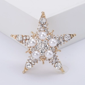 Elegante spilla a stella dorata con strass scintillanti e perle bianche su sfondo bianco