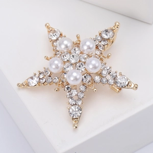Dettaglio della spilla a stella dorata con perle bianche e strass di cristallo brillanti