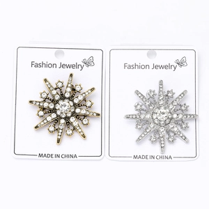 Detailed view of snowflake starburst brooches in gold and silver with crystal pavé