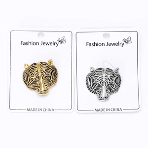 Detail view of vintage gold and silver tiger head alloy brooches on display card