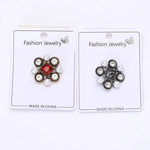 Detail of vintage Baroque style flower brooches with red and grey stones on a card