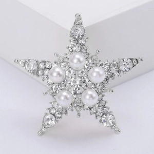 Dettaglio della spilla a stella d'argento con cristalli pavé e perle bianche
