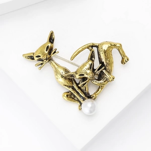 Detail of vintage gold alloy double cat brooch with white pearl inlay and engraved texture