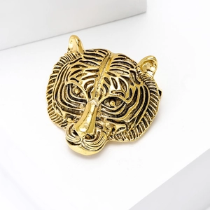 Detailed close-up of a vintage golden tiger head brooch with black embossed stripes