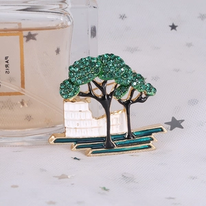 Macro shot of tree brooch featuring green crystals, gold metal, and Roman Colosseum detail