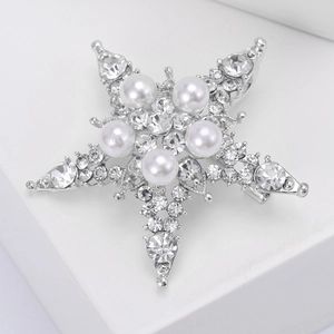 Spilla a stella elegante con perle bianche e strass su un supporto bianco semplice