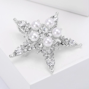 Dettaglio della spilla a stella con perle bianche e strass scintillanti su base argento