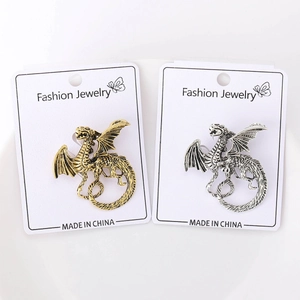 Detail of vintage dragon brooches in gold and silver finish on display cards