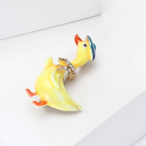 Spilla anatra gialla in smalto con fiocco di strass su sfondo bianco minimalista