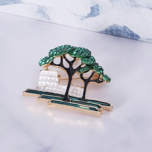 Detailed view of green crystal tree brooch with gold plated architectural base