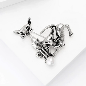 Detail shot of vintage silver twin cat brooch with a round white pearl on pedestal
