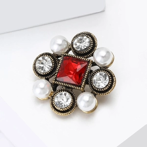 Detail of baroque brooch with square red ruby centerpiece, pearls, and crystals in gold setting