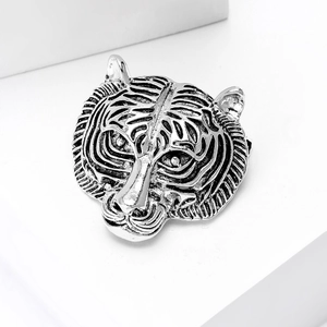 Detailed close-up of retro silver tiger head brooch with intricate carved metallic textures