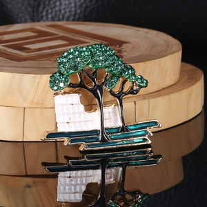 Detailed view of nature-themed tree brooch with green rhinestones on wooden base