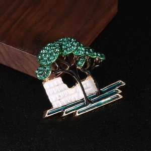 Detail of artistic tree brooch with green rhinestones and brick wall base design