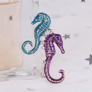 Detail of blue and purple enamel seahorse brooch with white rhinestones on fabric