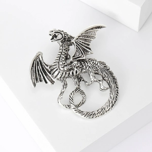 Detail of vintage silver alloy flying dragon brooch with intricate scale textures