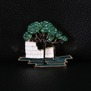 Close-up of alloy green tree and castle wall brooch with sparkling rhinestones